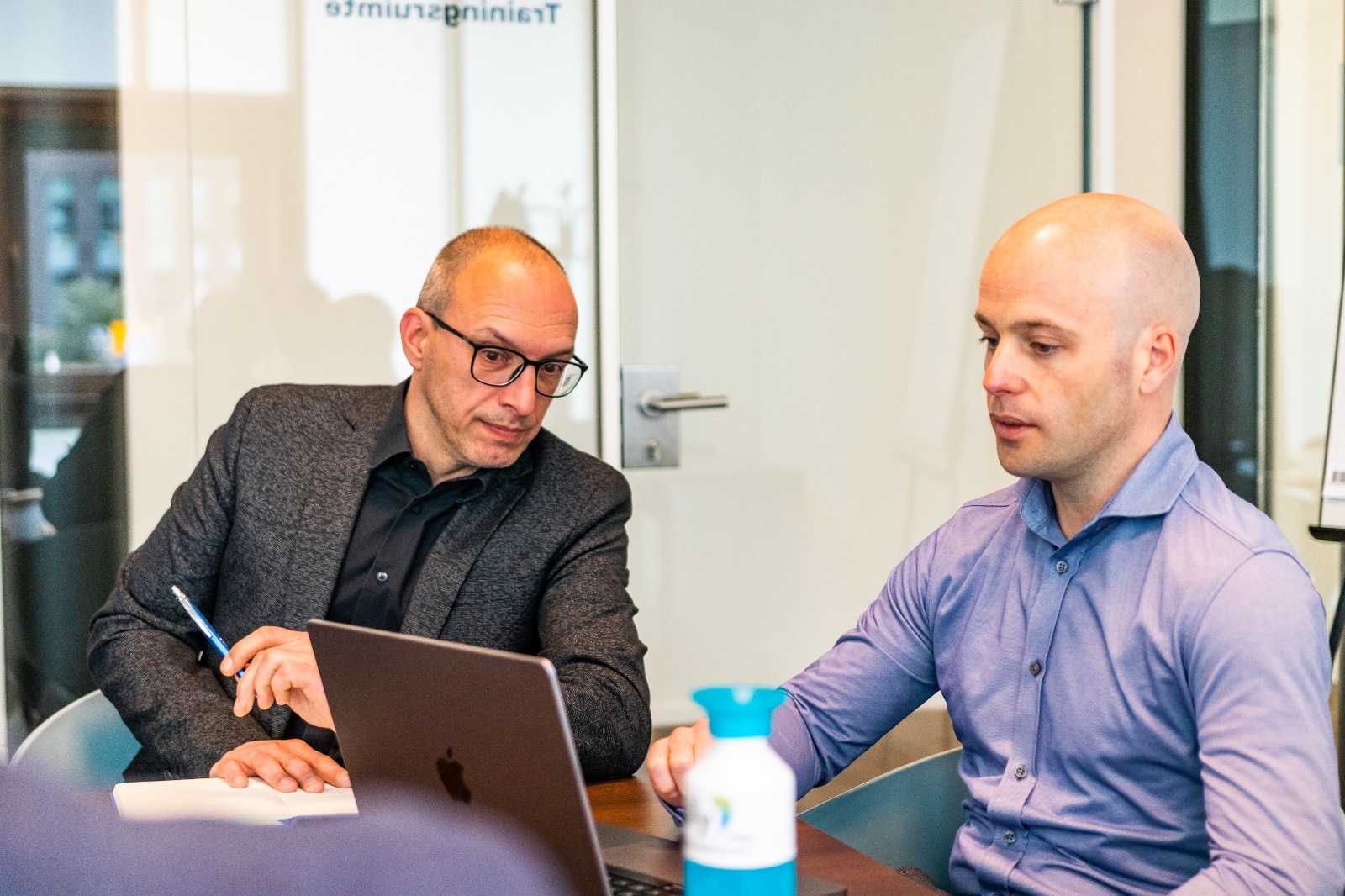 Twee leden van het Polly.Help-team die samen aan een laptop werken